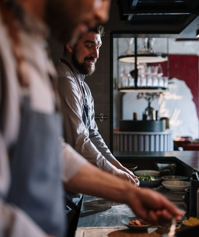 Two chefs preparing dishes in an open restaurant kitchen