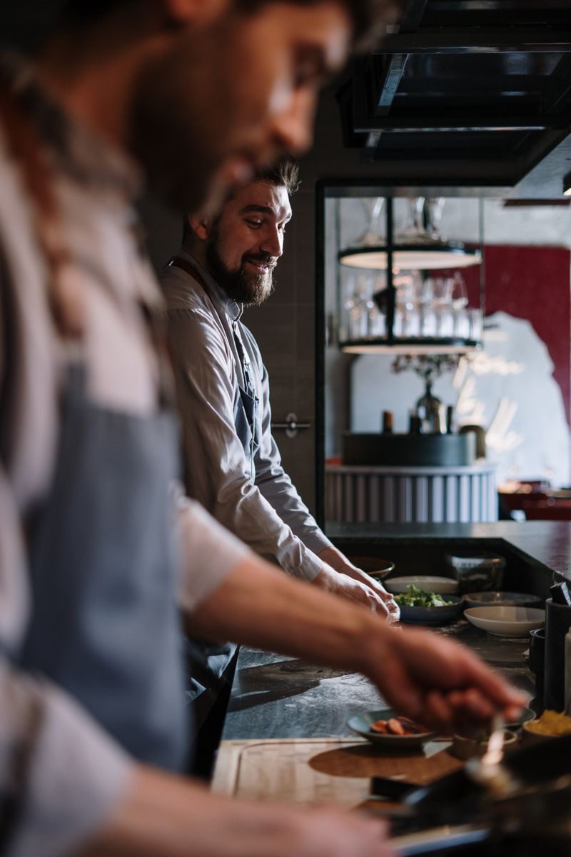 Deux cuisiniers préparant des plats dans une cuisine professionnelle