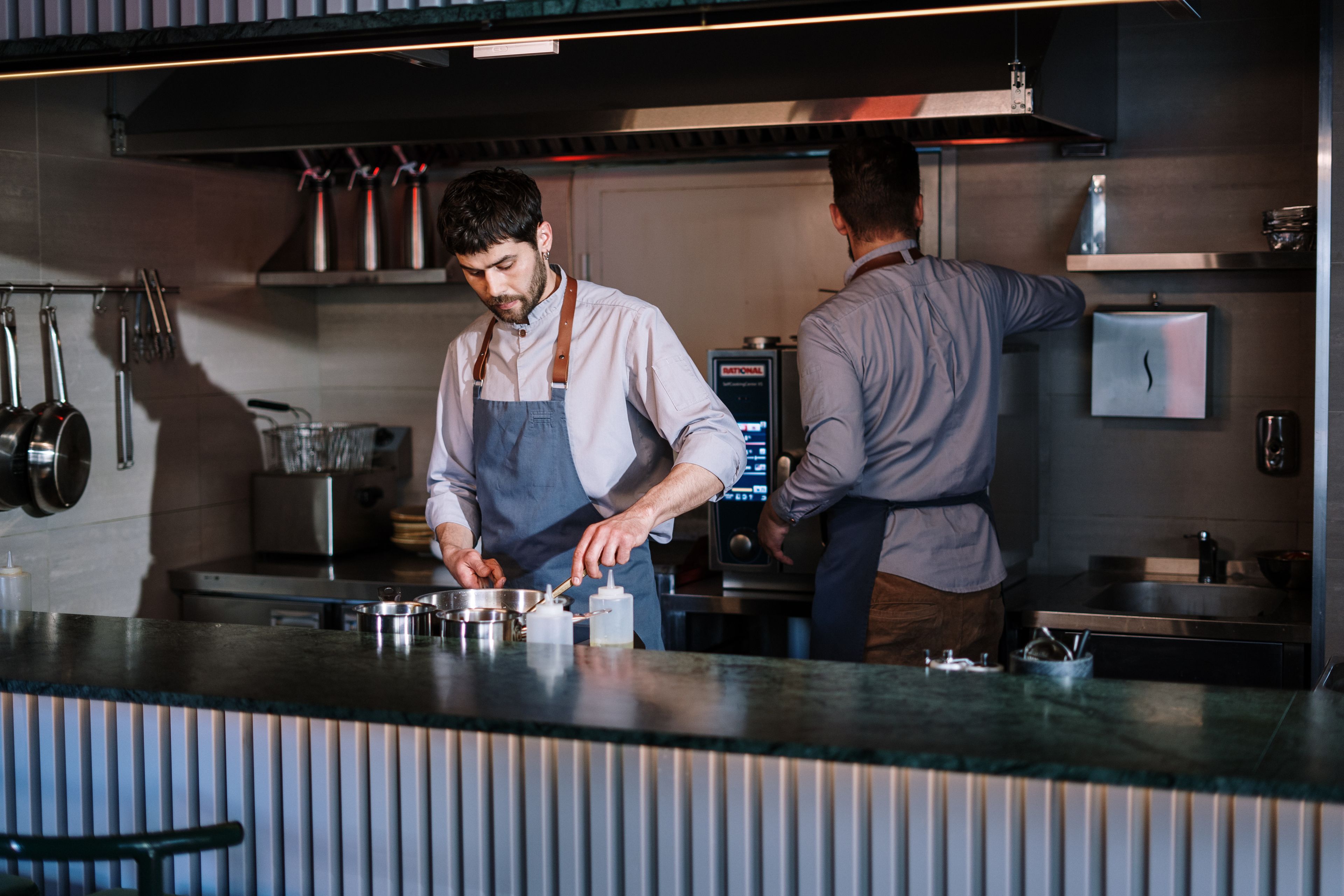 Cuisine ouverte de brasserie où deux cuisiniers assurent le service en continu