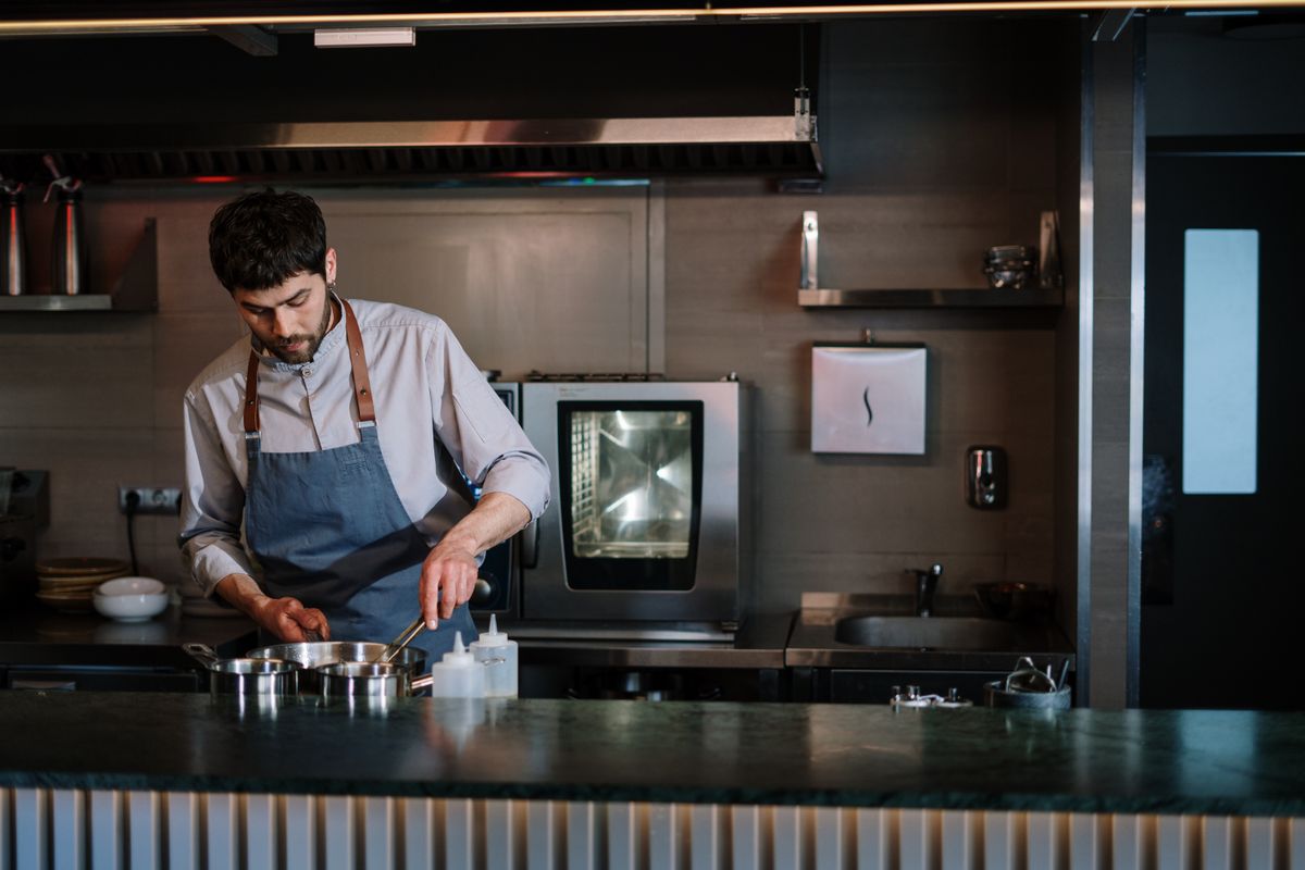 Chef in a blue apron at an open kitchen counter