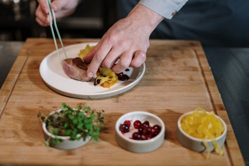 Person Slicing Meat on Brown Wooden Chopping Board