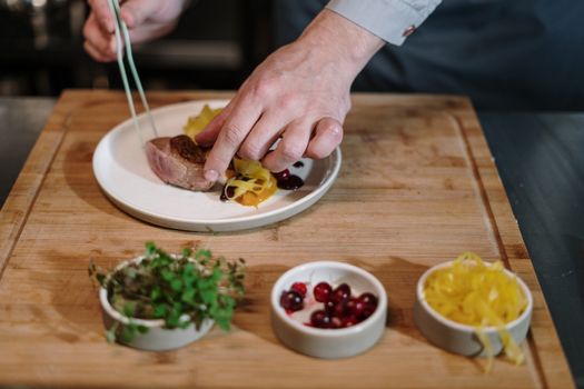 A chef carefully plates a gourmet dish with precision in a modern kitchen setting.