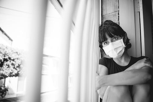 Grayscale Photo of a Lonely Woman Wearing Face Mask