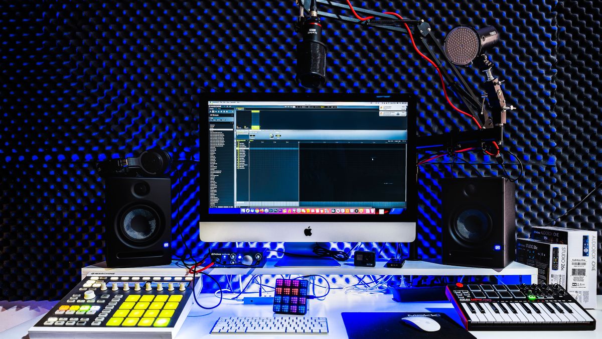 Digital music production workspace with computer, speakers and recording equipment
