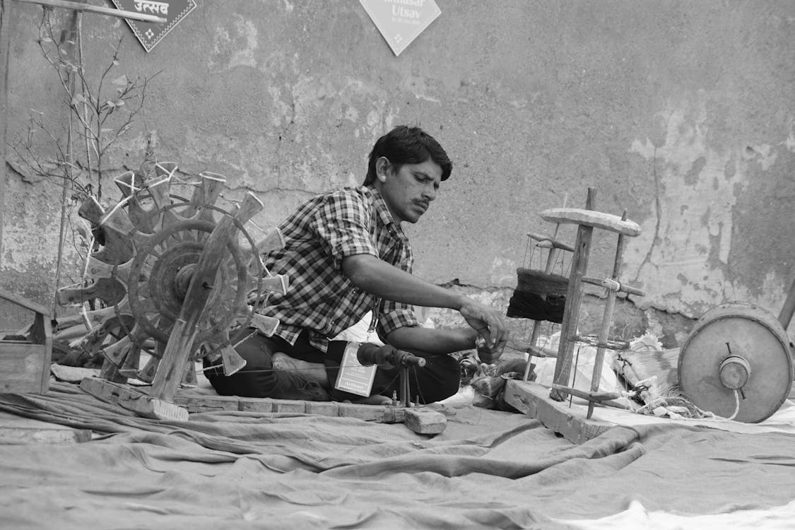 Serious ethnic man weaving textile on street · Free Stock Photo