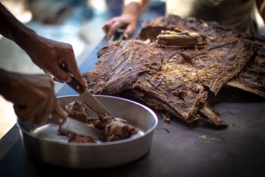 Delicious Brazilian ribs being sliced on a tray, showcasing traditional costela preparation.