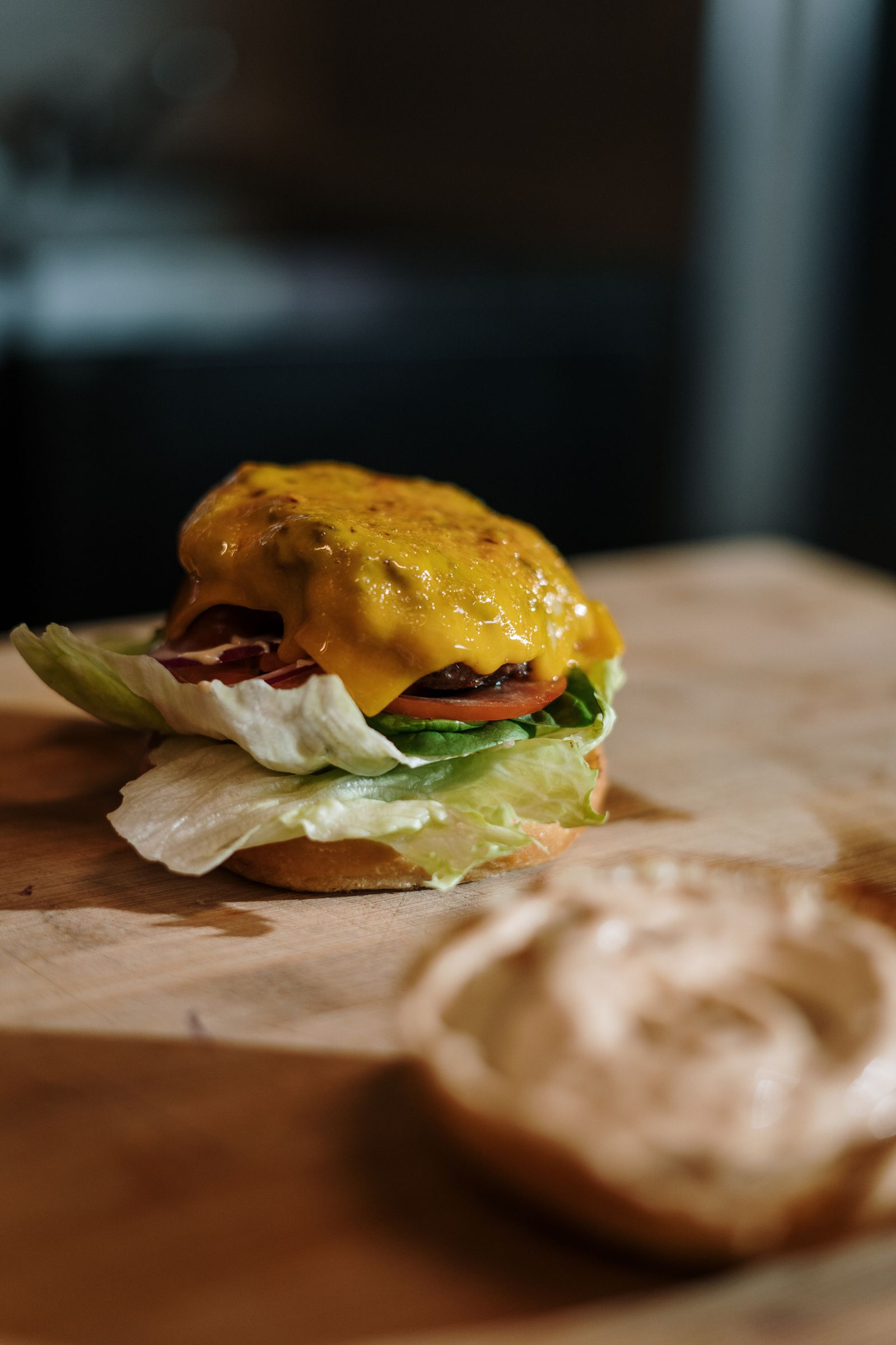 Close-up of a smash burger with melted cheese, lettuce and tomato on a wooden board