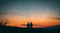 一对夫妇在乡村充满活力的日落映衬下牵着手