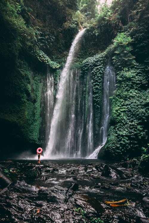 Person in Red Jacket Standing in Front of Waterfalls
