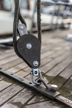High angle of swivel sheave with rigging rope on wooden deck of sailing ship moored in harbor
