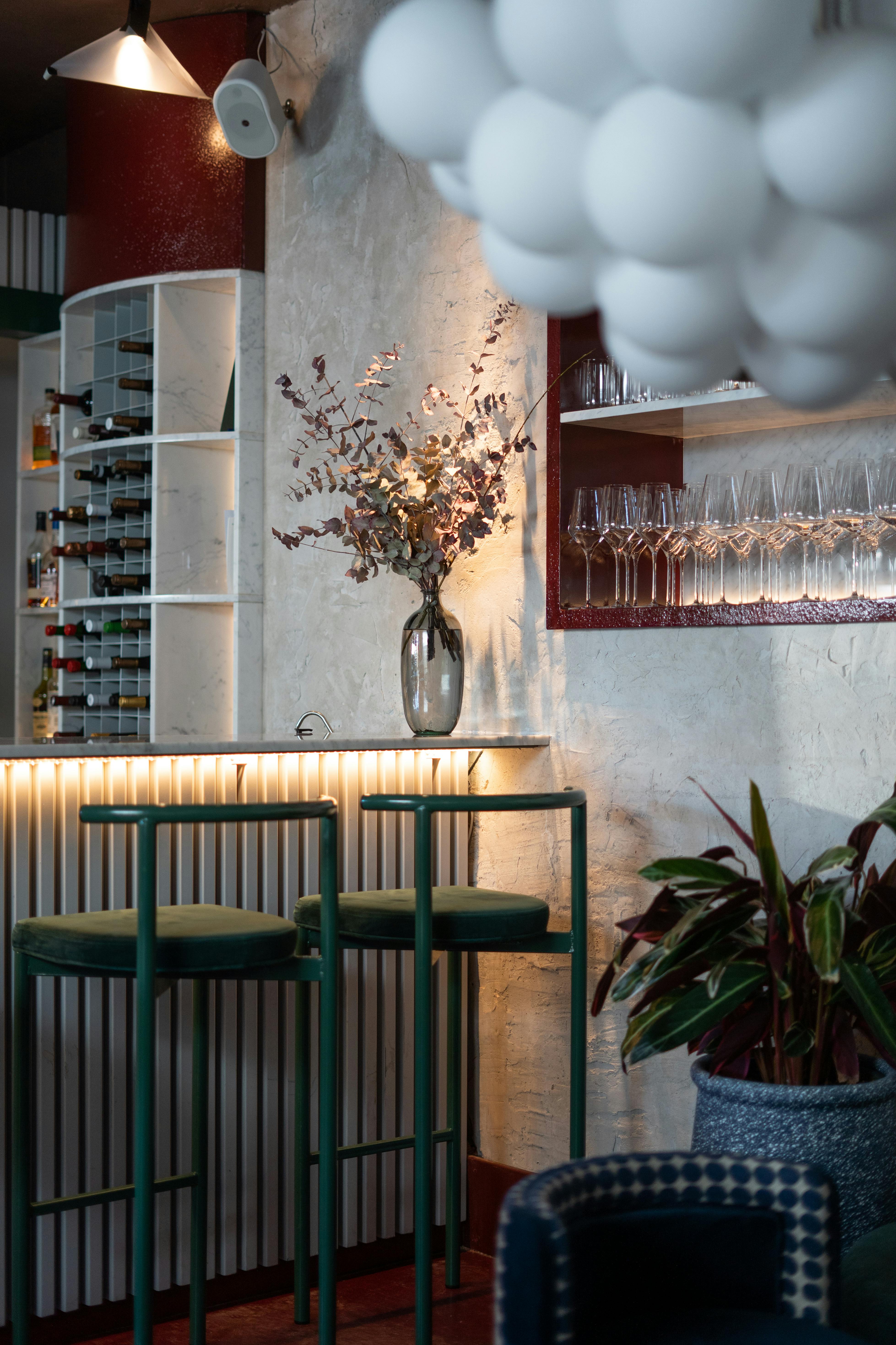 Stylish bar setting featuring wine shelves, a vase, and modern lighting for an inviting atmosphere.