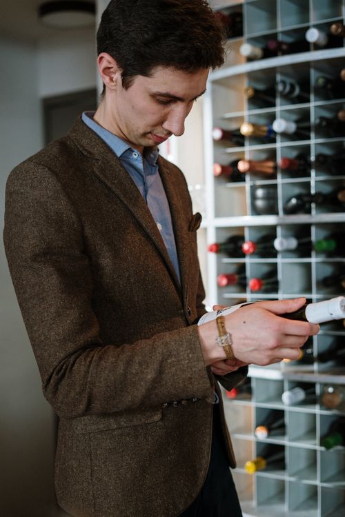 Free A sommelier examines a wine bottle in a contemporary wine cellar with a diverse wine collection. Stock Photo
