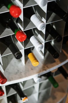 Various wine bottles stored in a geometric wine rack, offering a close-up of bottle tops with a mix of colors.