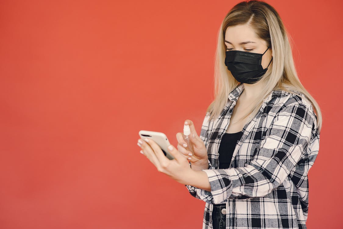 Young woman disinfecting smartphone during coronavirus pandemic