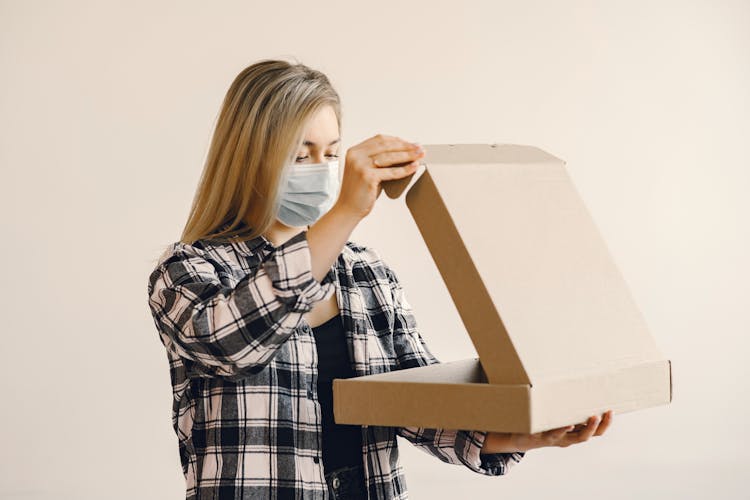 Young Woman In Medical Mask Opening Pizza Box