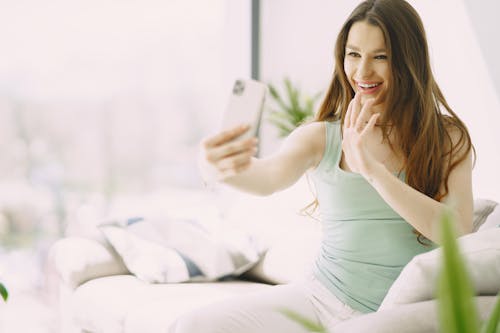 Free Cheerful young woman using smartphone during video call Stock Photo