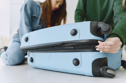 Free Young women closing luggage bag on floor Stock Photo