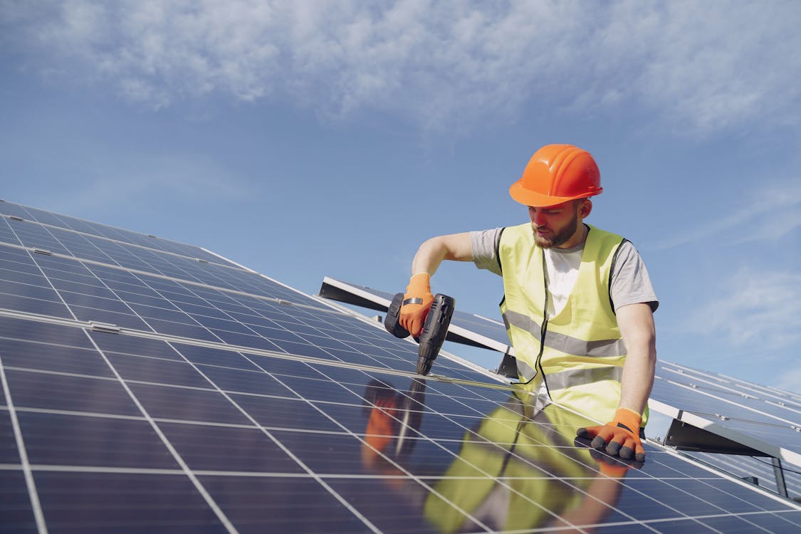 Man fixing solar panels with professional drill