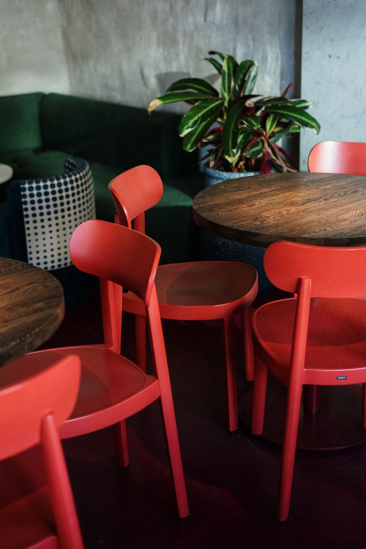 Bold red bentwood-style dining chairs around a round wooden table