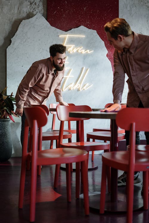 Man in Brown Dress Shirt Sitting on Red Plastic Chair