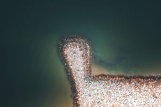 Amazing aerial view of curvy stony pier located in clean calm sea on sunny day