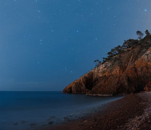 Free Rocky hill on sea shore against starry sky Stock Photo