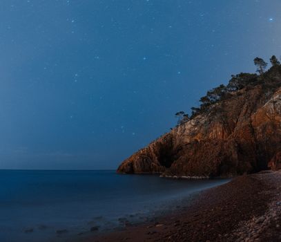 星空下，宁静的海岸线展现着崎岖的悬崖与夜晚平静的大海
