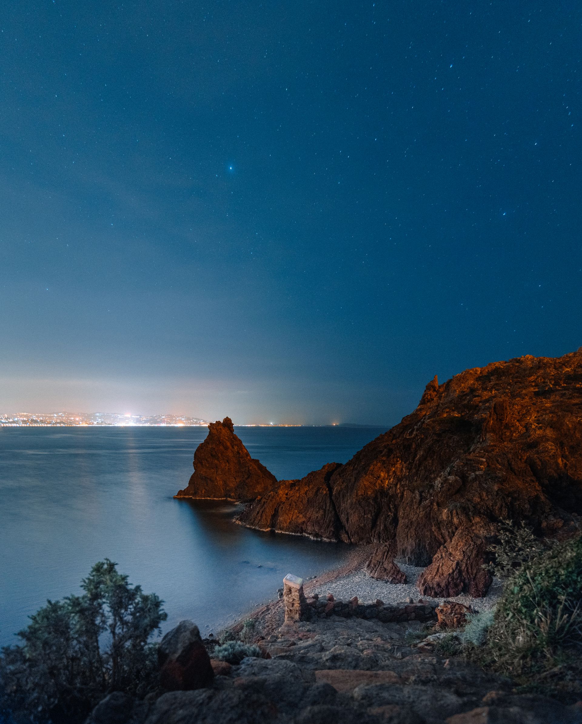 A rocky stretch of coast under a clear night sky full of stars