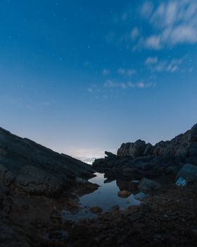 星空下，宁静的夜间沿海风光中，海岸多岩石