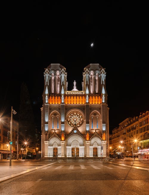 Lighted ancient Catholic gothic style cathedral located on empty street in historic district at night time