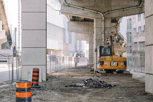 Free Site of roadway under concrete bridge construction with heavy equipment on dirty ground Stock Photo