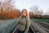 秋天，一位穿着高领毛衣的年轻女子站在铁路上，望着远方，做着白日梦