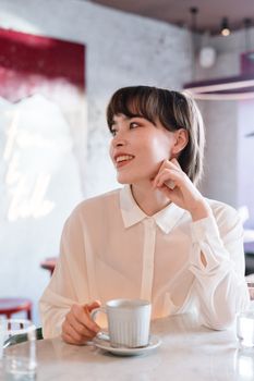 一位时尚女士在别致的咖啡馆里微笑着享用咖啡，这正是完美生活方式的写照