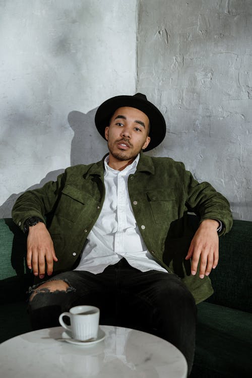 Man in Green Suit Jacket and Black Pants Sitting on Green Chair