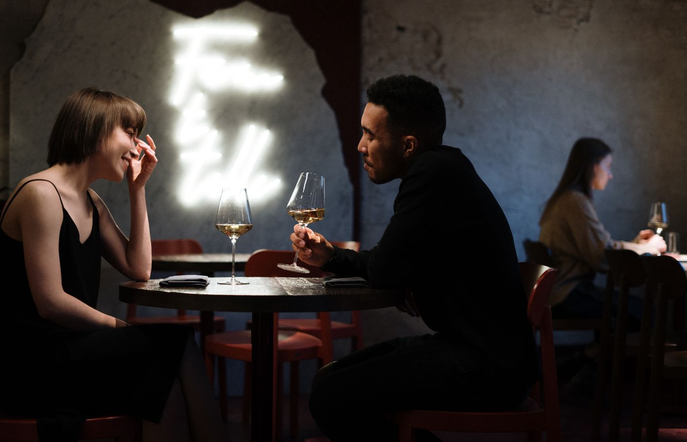 Couple enjoying a romantic evening with white wine in a stylish bar setting.
