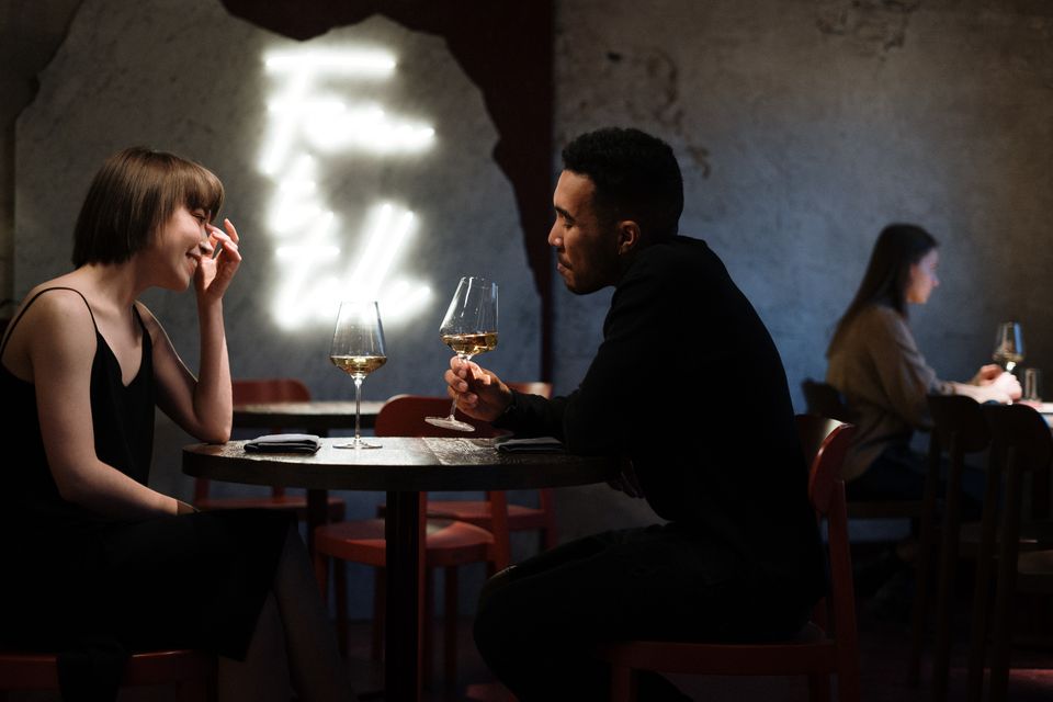 A couple sharing white wine at a stylish bar