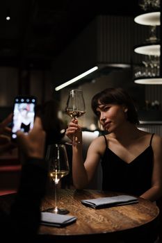 在高档餐厅享用浪漫晚餐时喝白葡萄酒的女人