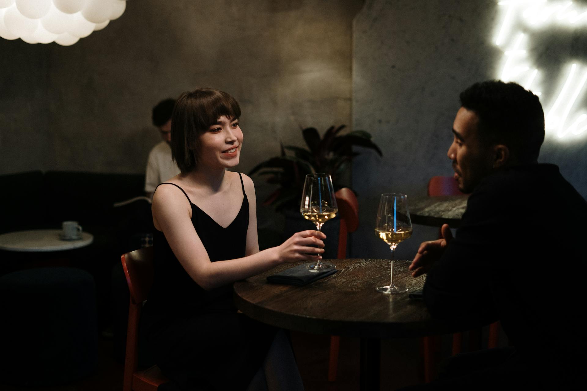 Couple enjoying a date night with white wine in a modern restaurant.