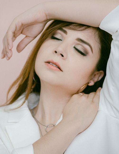 Elegant portrait of a woman in white with closed eyes, exuding serenity and grace.