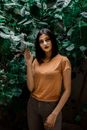 一位优雅的女子立于繁茂的枝叶间，周身散发着从容与自信