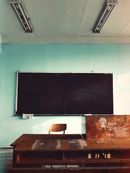 Empty classroom with a chalkboard, wooden desk, and chair, evoking a vintage educational setting.