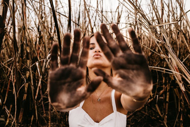 Woman Giving Five With Dirty Palms Of Hands In Field