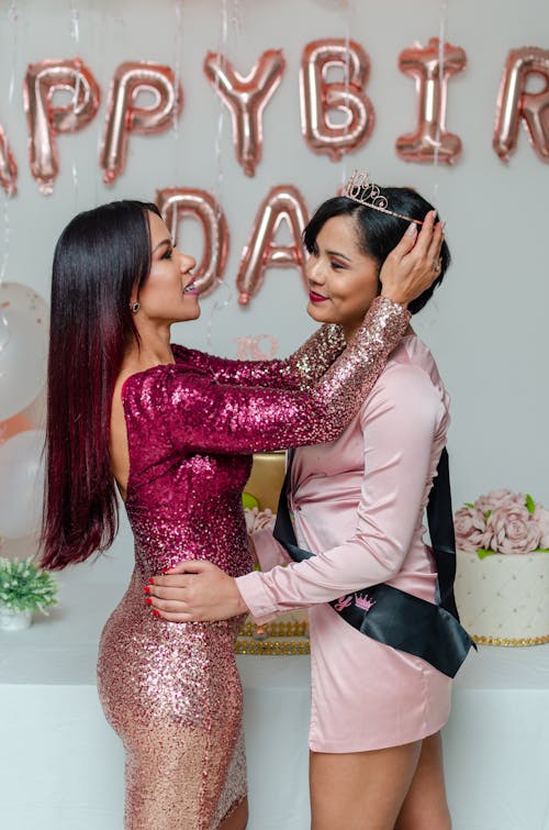 Woman in Pink Glittery Dress Putting on a Tiara on the Birthday Celebrant