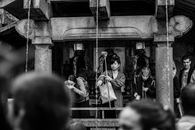 Black and white of multiracial tourists drinking holy water while standing near old stone construction with narrow vertical pouring flows in sacred place
