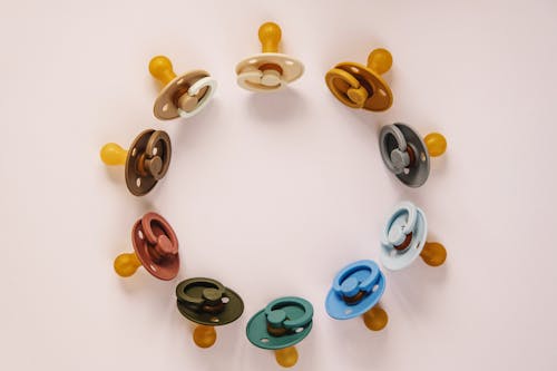 Set of multicolored baby pacifiers on table