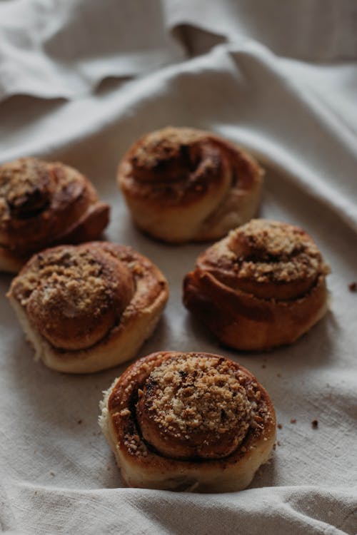 From above of delicious brown baked cinnamon rolls with soft texture and streusel crumb topping on linen towel at home