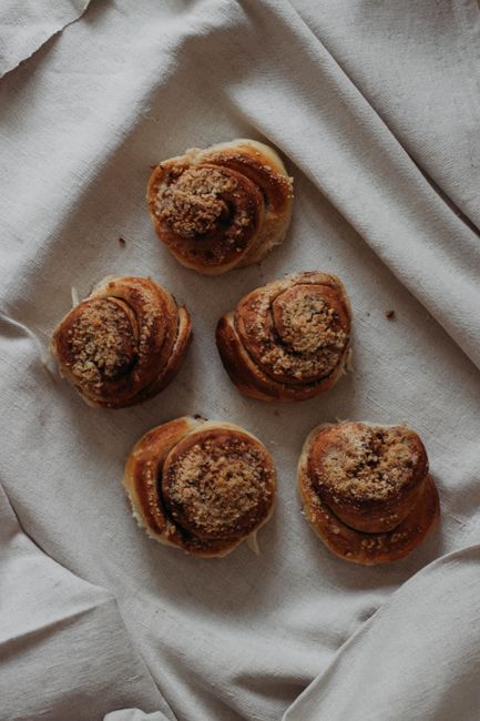 Top view of similar homemade brown tasty cinnamon rolls with on towel in tray in kitchen