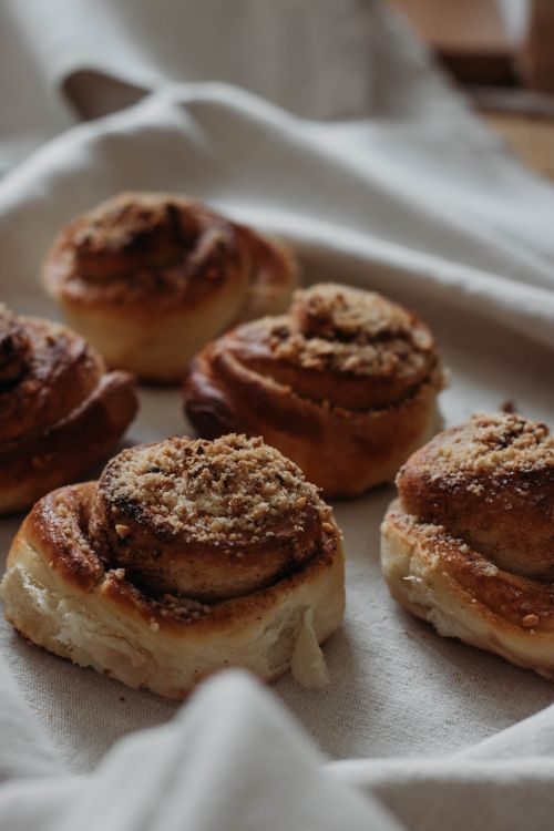 Free From above of similar baked sweet cinnamon buns with brown surface and soft texture on crumpled linen towel on tray in flat Stock Photo