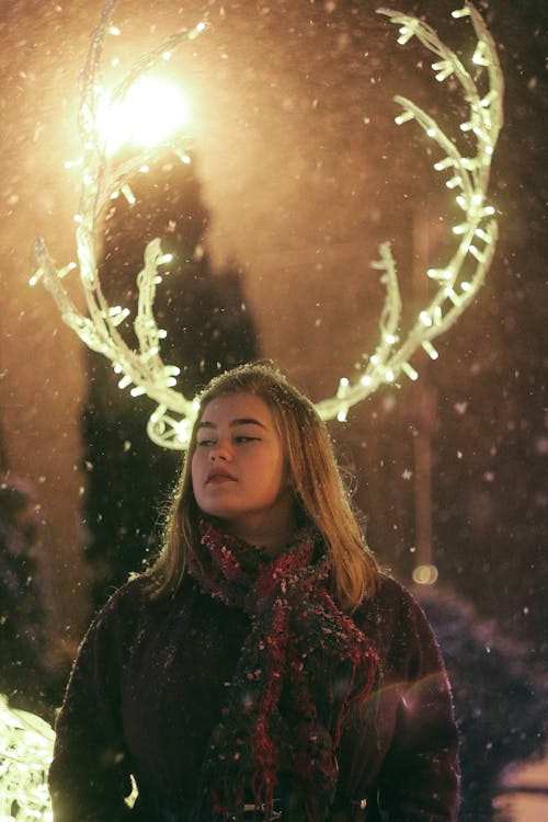 Cool woman near decorative shining deer horns during Christmas