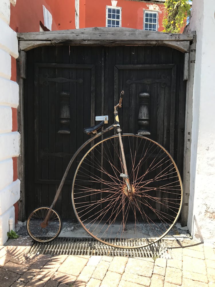 Old Penny Farthing Parked On Street Pavement In Sunlight